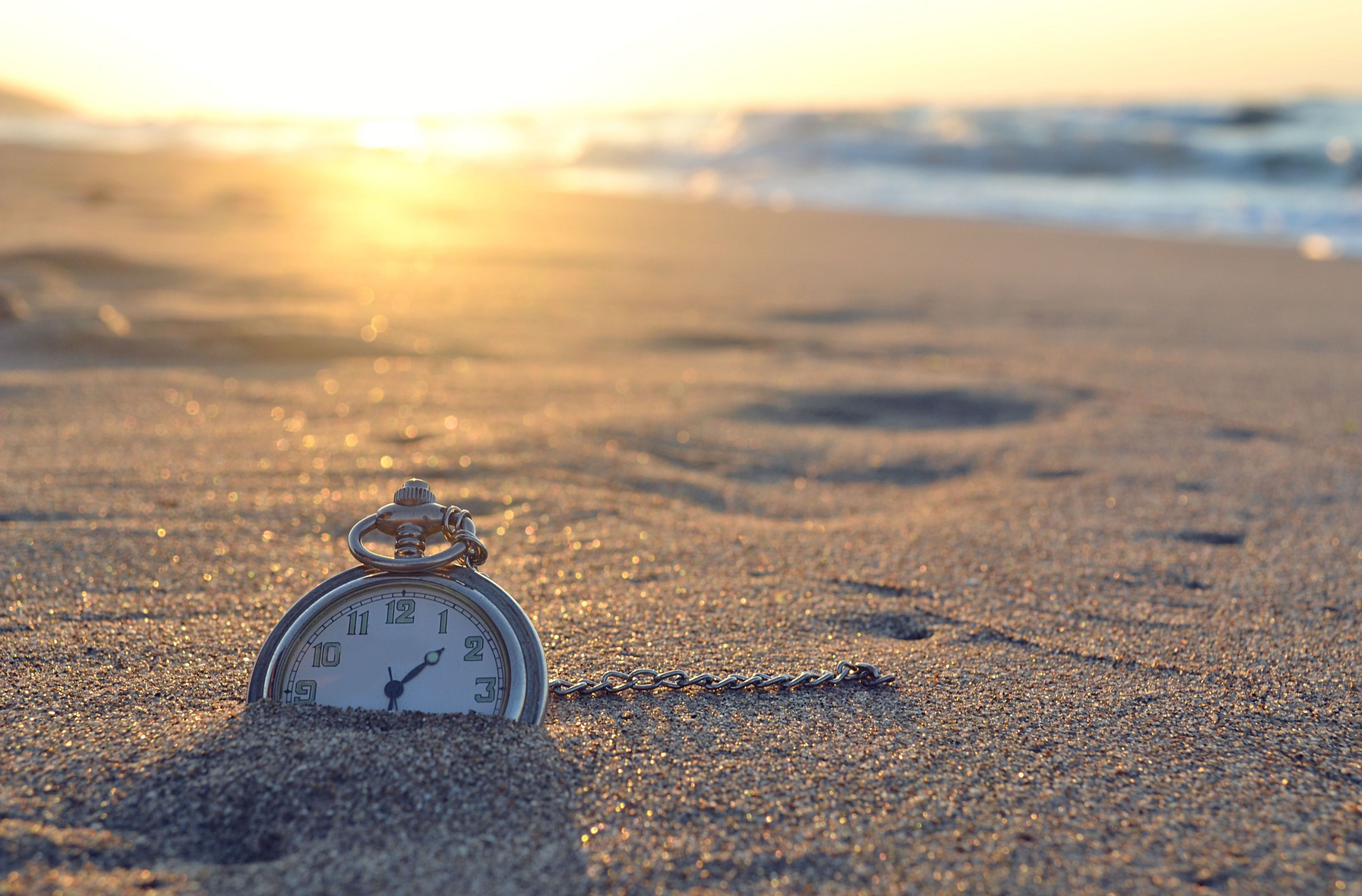 Pocket watch on the beach the meaning of time leaving its footprints