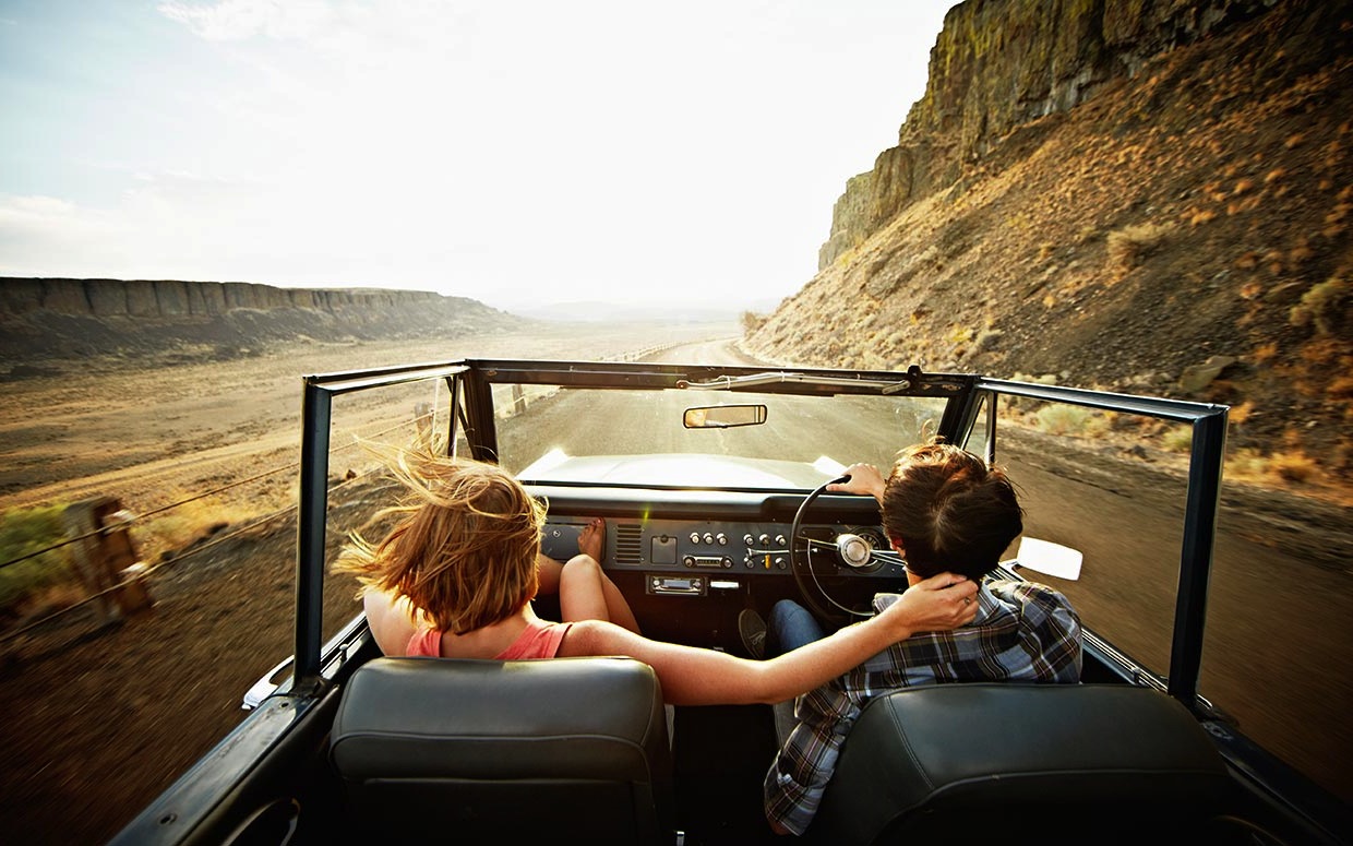 Couple in convertible driving holiday on empty roads bespoke trip