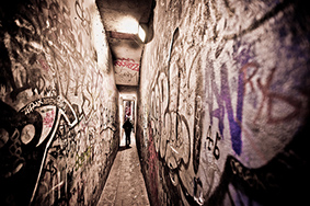 Narrow dark alley surrounded by graffiti sprayed walls discover the secrets at the end