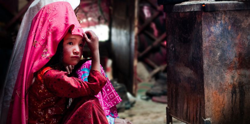 Kirghiz girl in yurt, taking refuge next to a stove, in Afghanistan