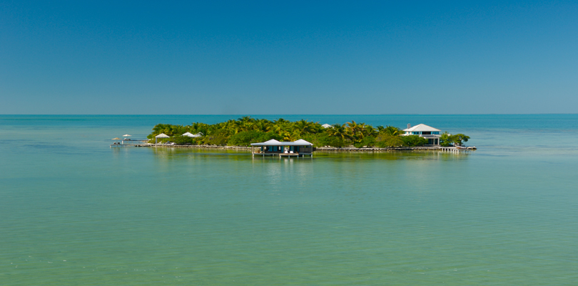 Tiny flat island in the middle of the ocean huts on stilts