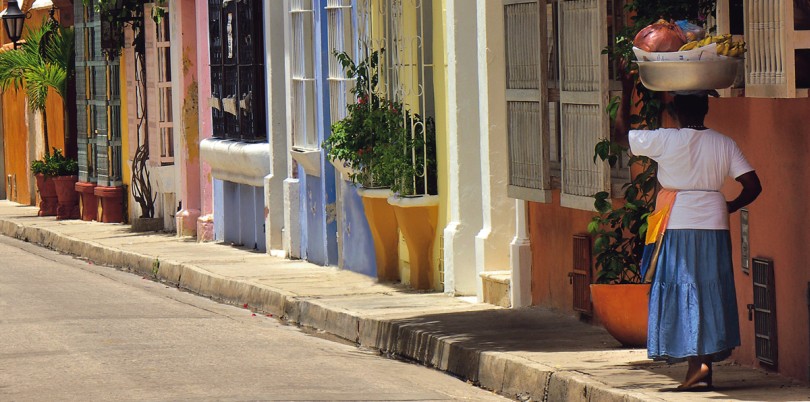 Colourful houses in Cartegena de Indias Columbia woman balancing a basket on her head