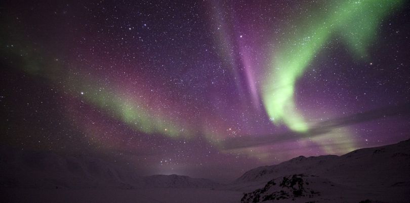 Northern Lights over a mountain range, purple and green, Greenland