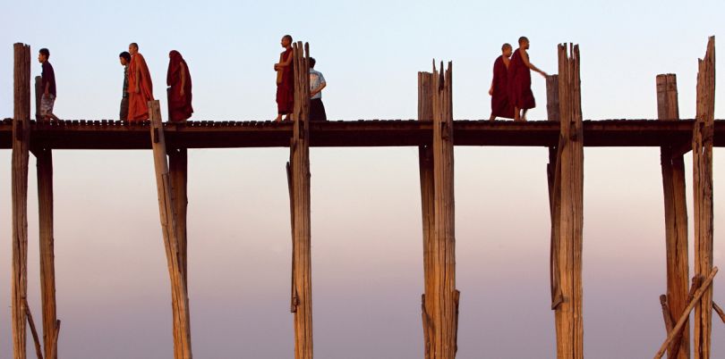 Monks walking over a bridge on stilts in Myanmar