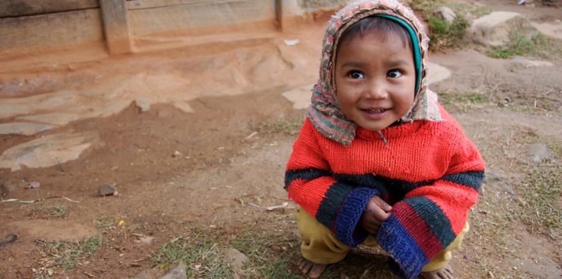 Little Nepalese girl barefoot squatting 